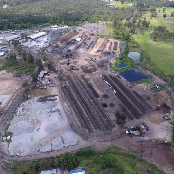 An aerial view of a large dirt field surrounded by trees and grass.