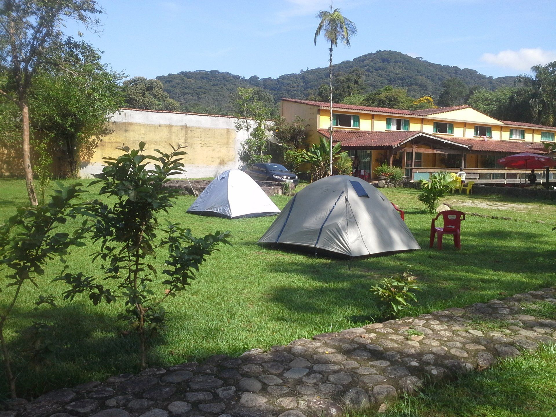Duas tendas estão sentadas em um campo gramado em frente a um prédio