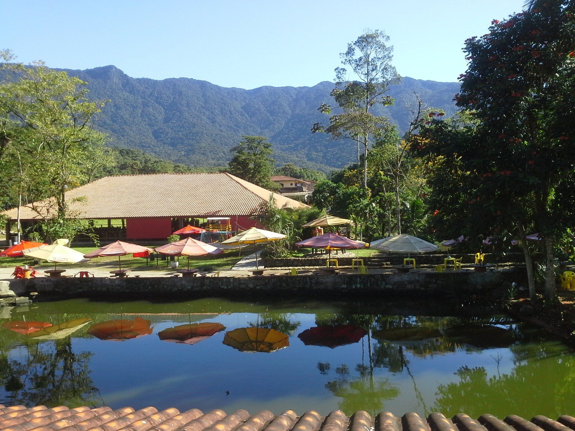 Um lago em frente a uma casa com montanhas ao fundo