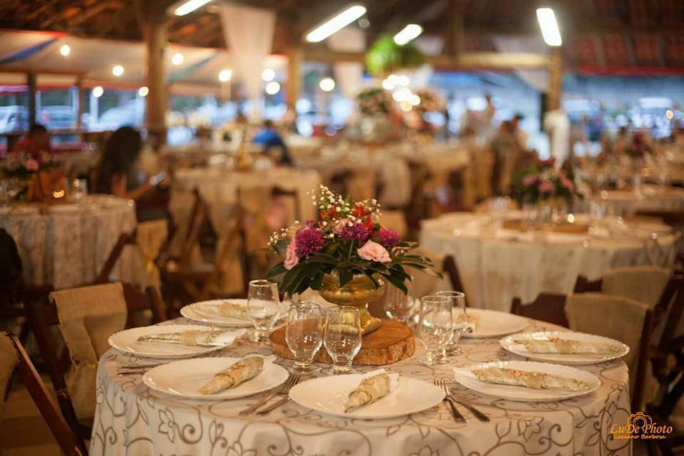 Uma mesa posta para uma recepção de casamento com pratos, copos e flores.