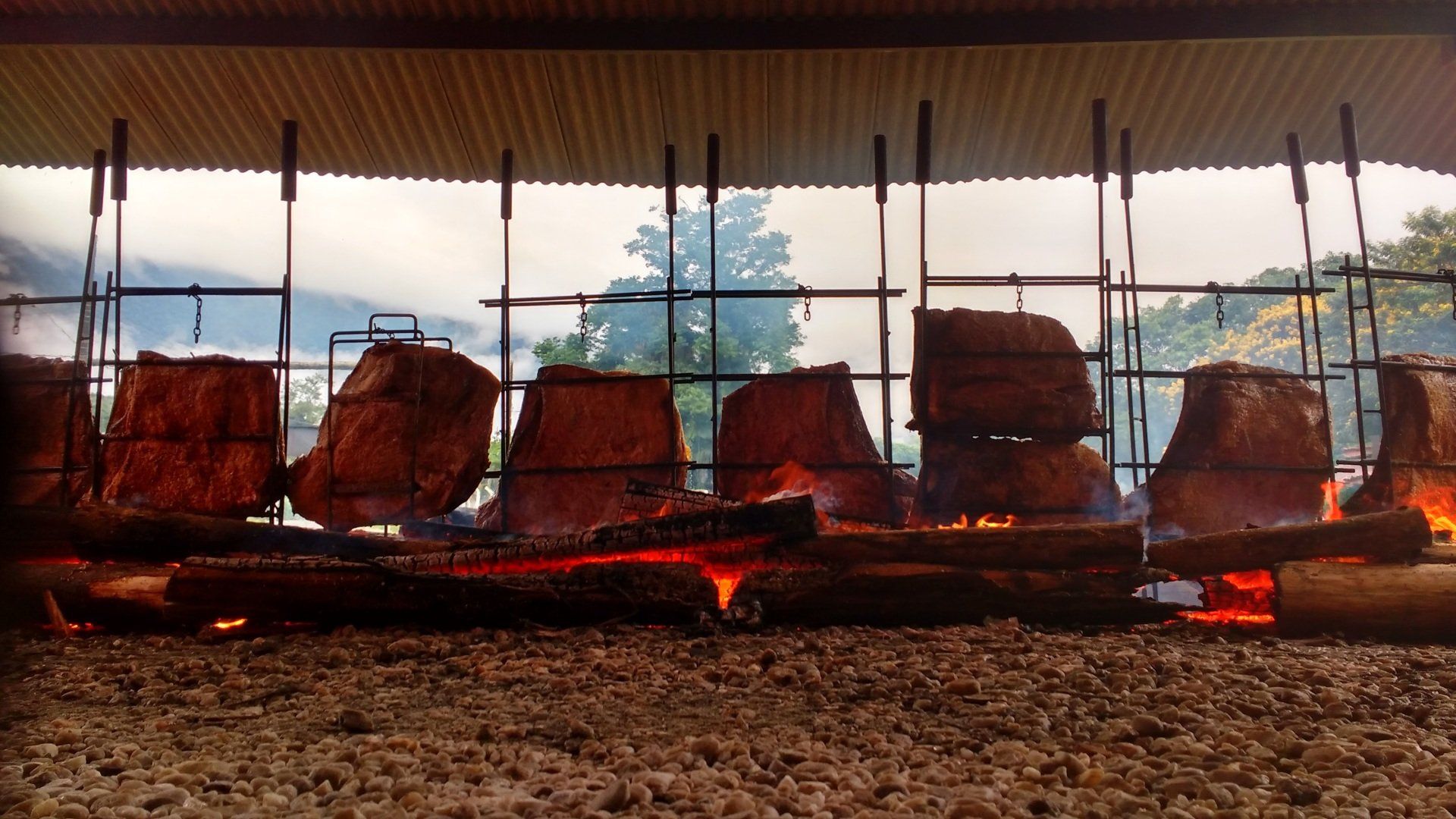 Uma grande quantidade de carne está cozinhando em uma grelha