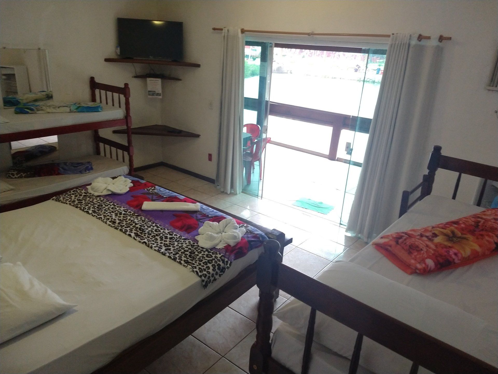 Um quarto com duas camas e porta de vidro deslizante