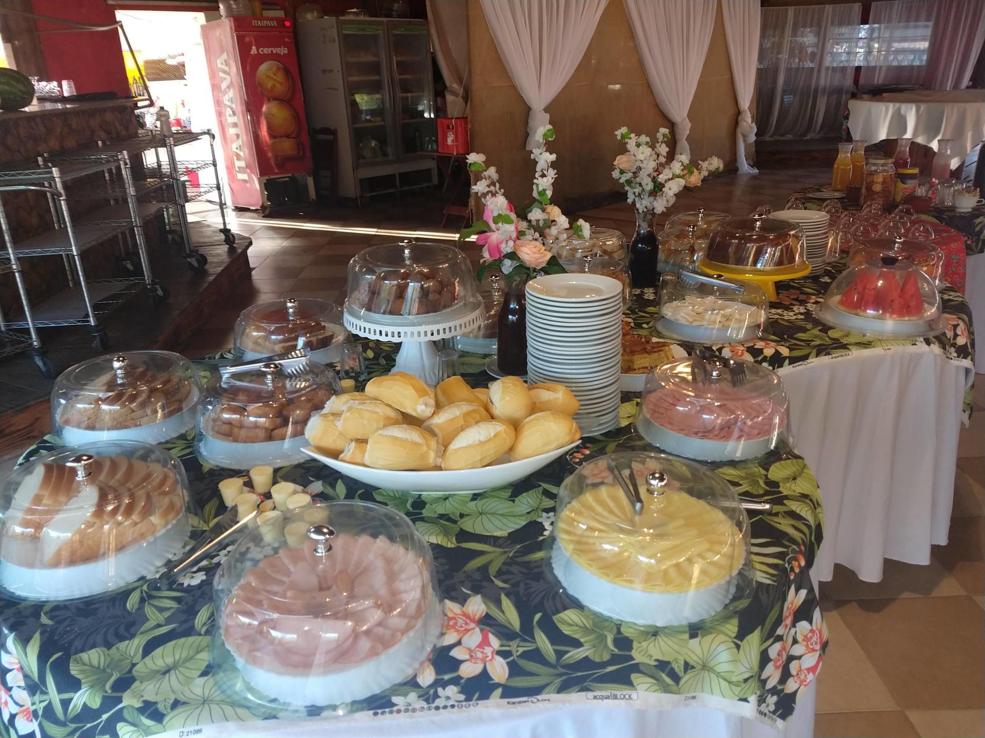 Uma mesa com muita comida e uma geladeira de coca-cola ao fundo