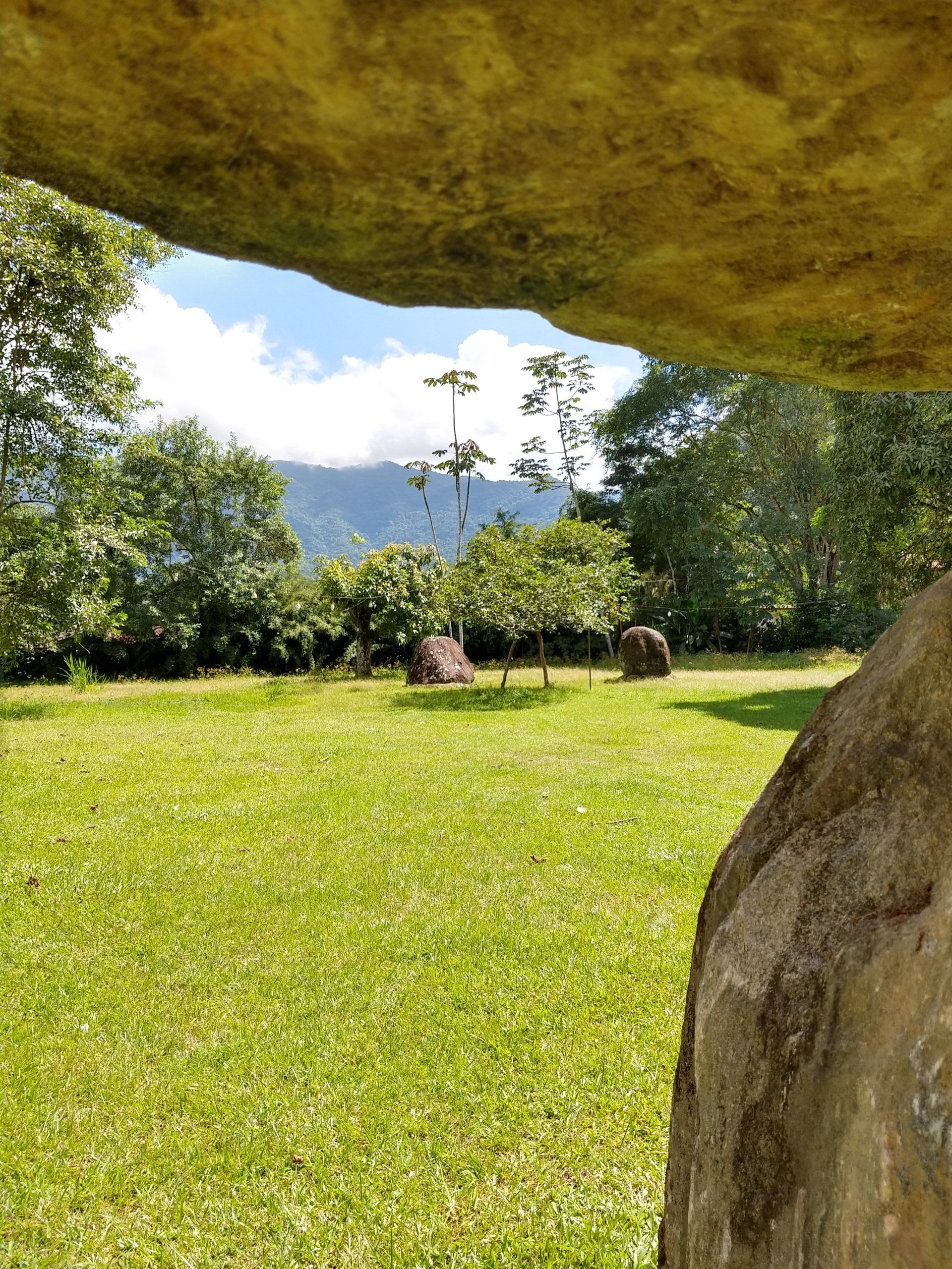 Uma grande pedra está no meio de um campo gramado.