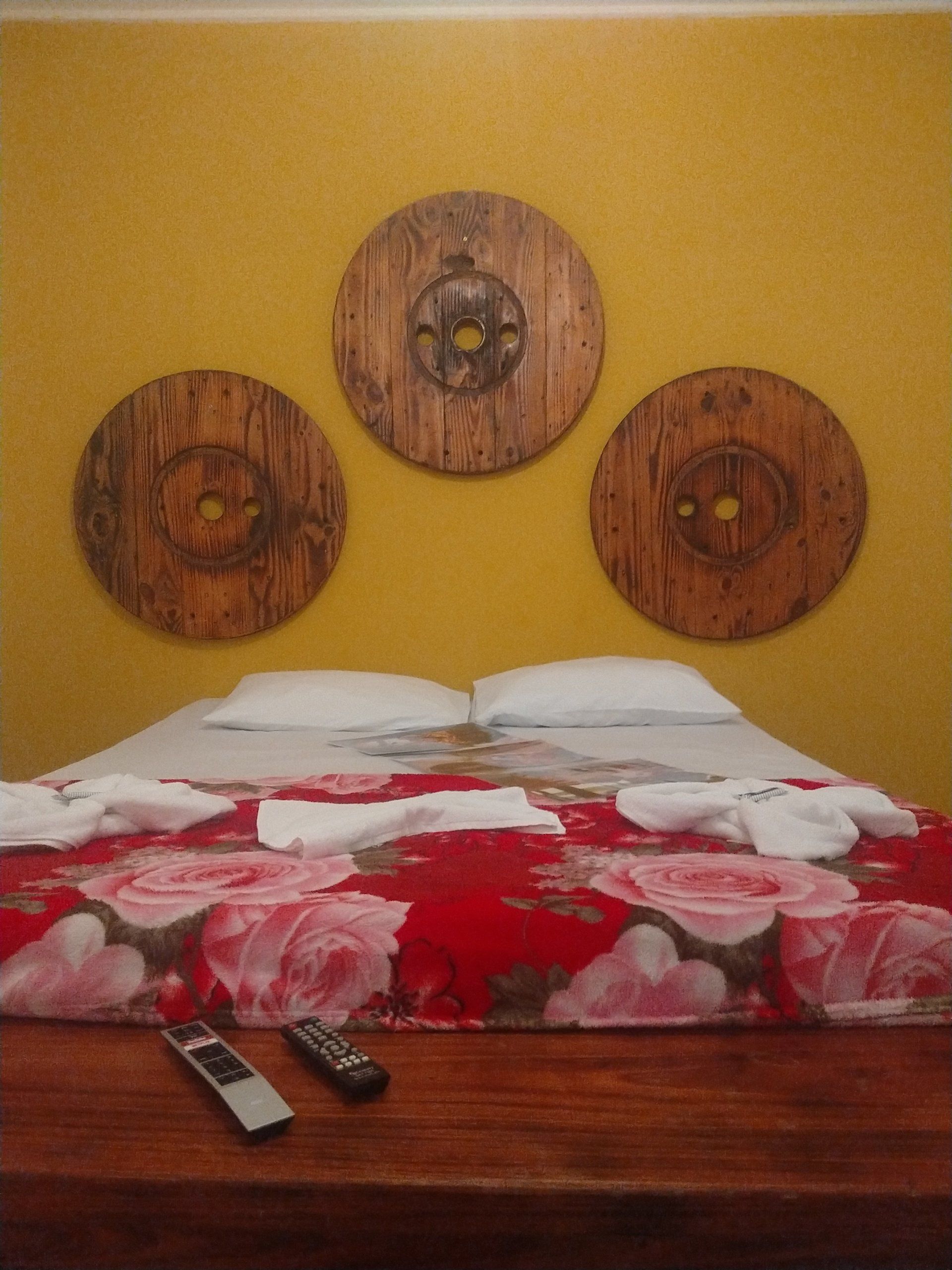 Uma cama com três escudos de madeira na parede acima dela