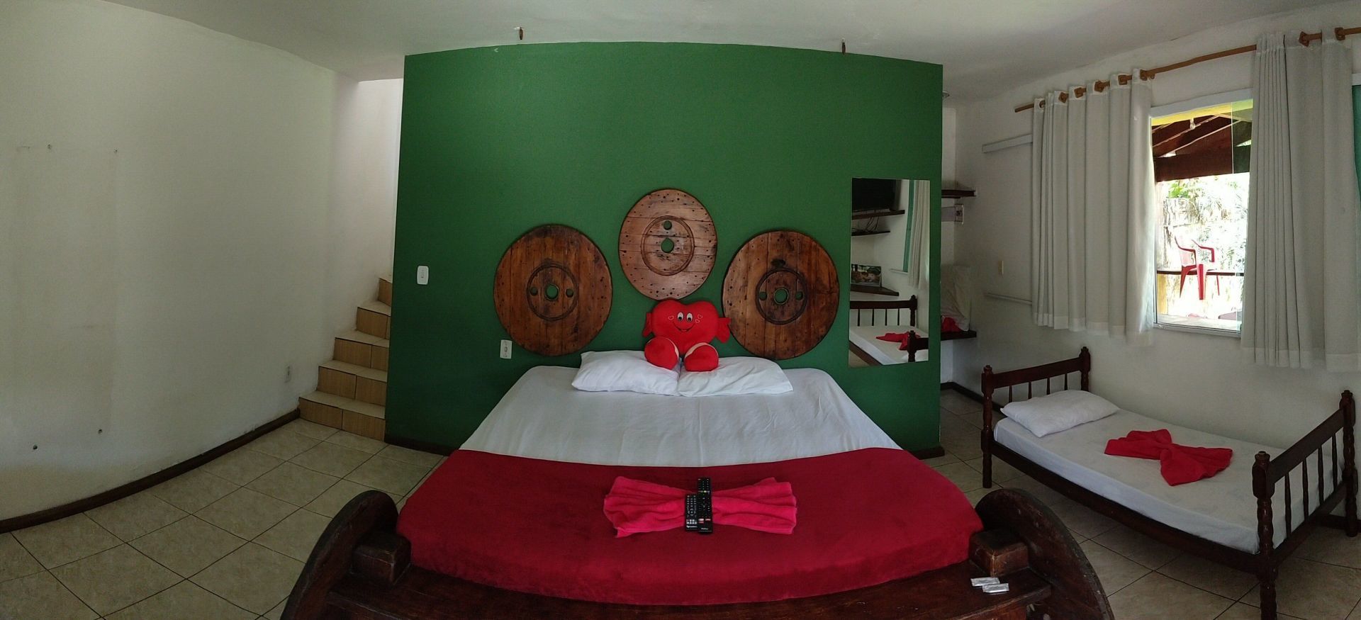 Um quarto com uma cama, duas camas e uma parede verde.