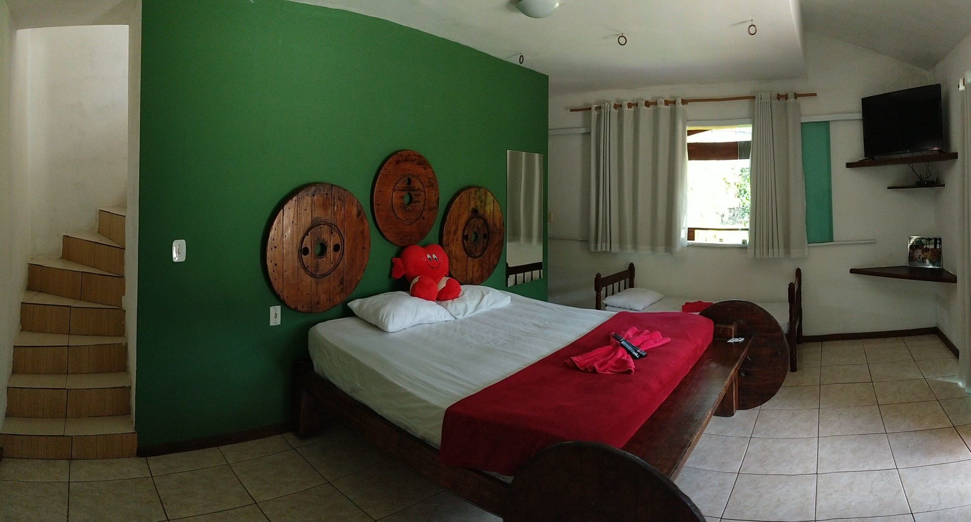 Um quarto com cama, escadas e parede verde.