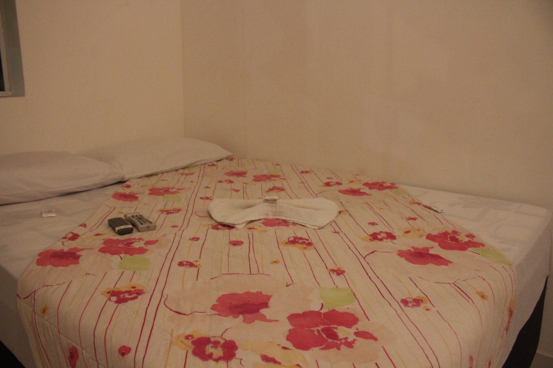 Uma cama com um cobertor floral e toalhas