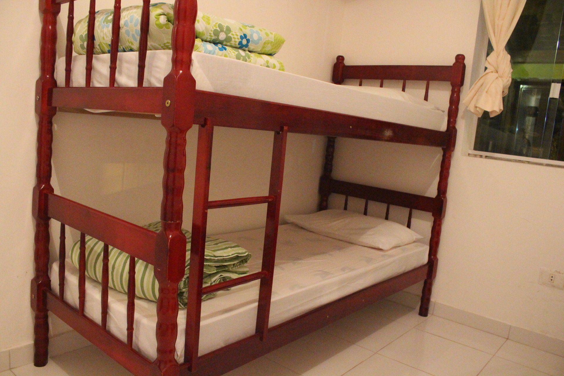 Um beliche está em um quarto próximo a uma janela.