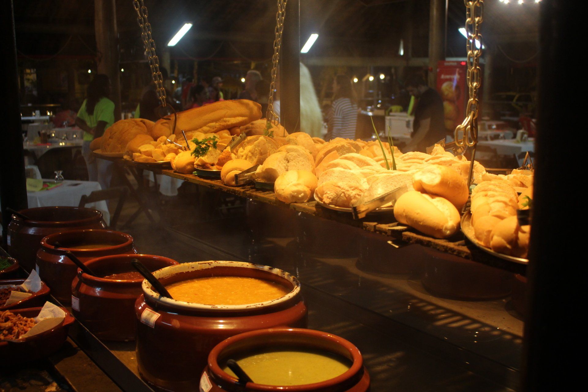 Vários potes de sopa e pão estão expostos em um restaurante