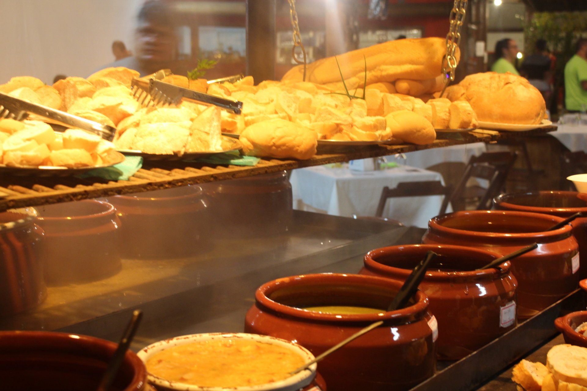 Uma mesa de bufê com muito pão e panelas de sopa