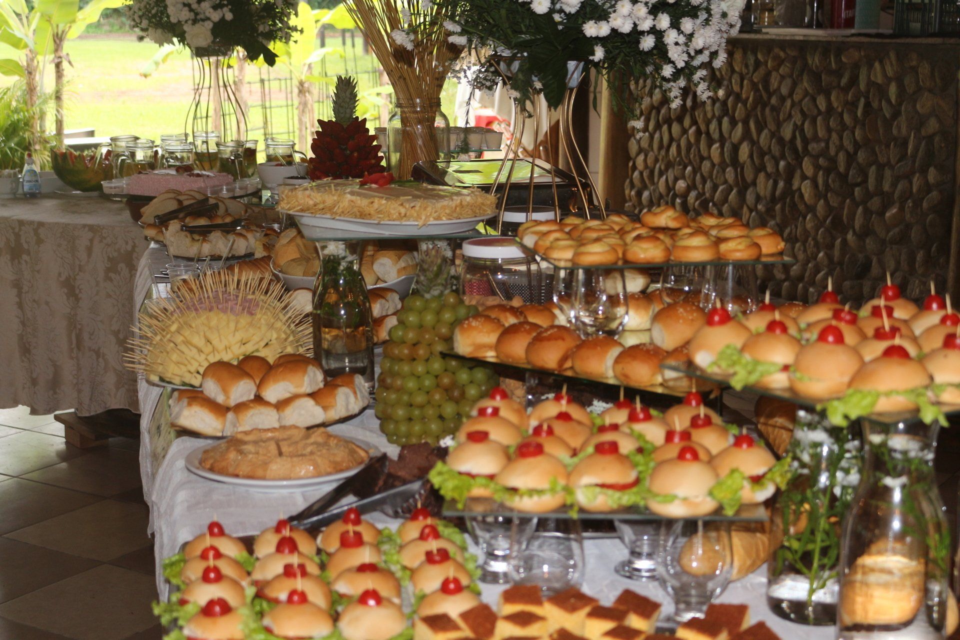 Uma mesa de buffet cheia de muita comida, incluindo hambúrgueres