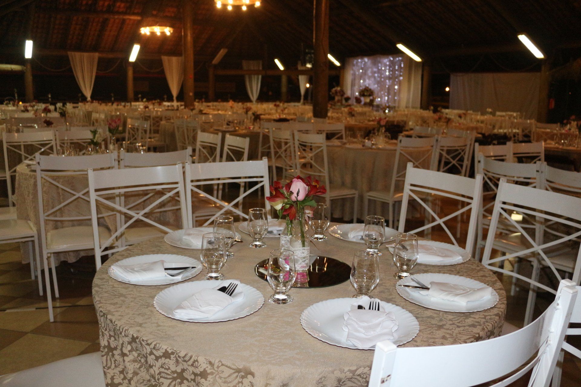 Uma grande sala com mesas e cadeiras preparadas para uma recepção de casamento