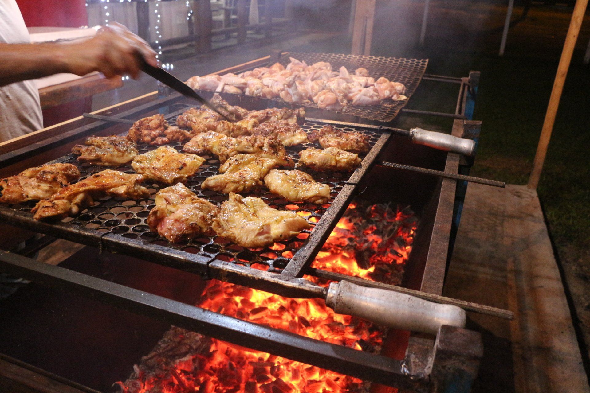 Uma pessoa está cozinhando carne em uma grelha no fogo.