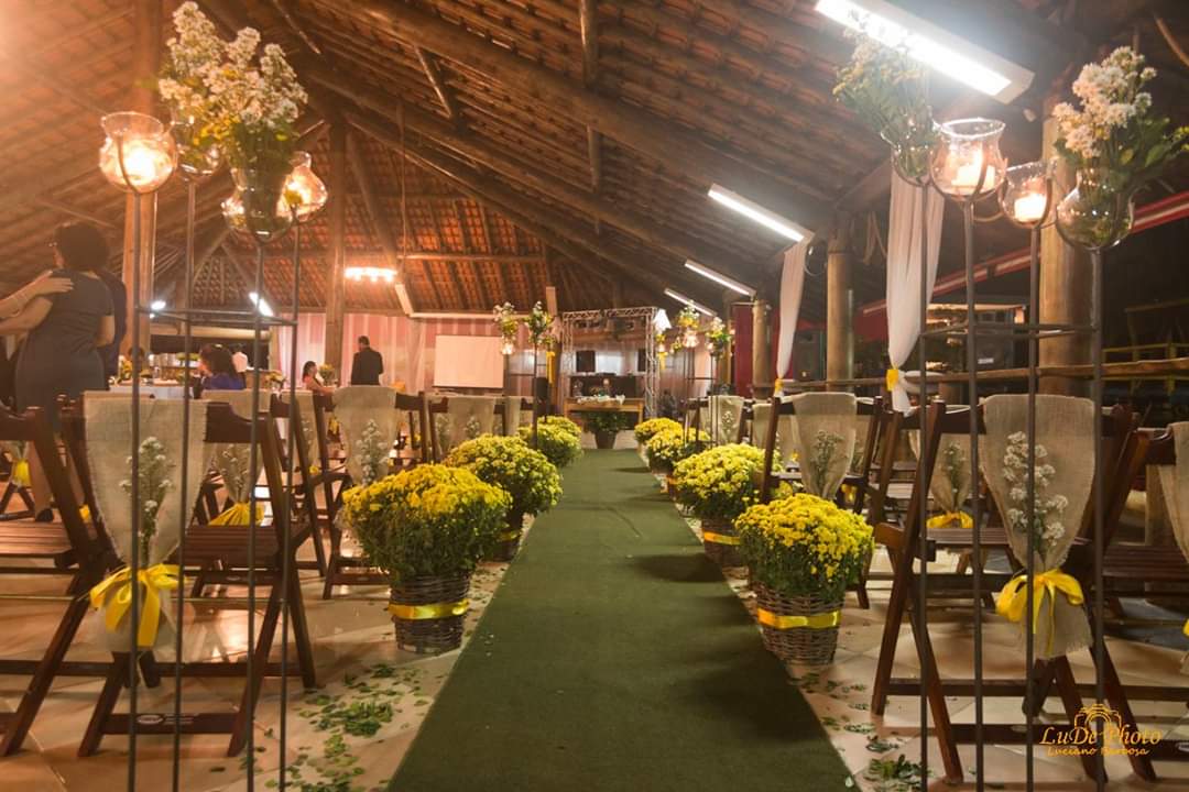 Um longo corredor decorado com flores amarelas e velas para uma cerimônia de casamento.