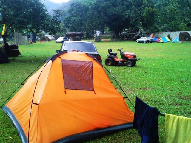 Uma barraca laranja está no meio de um campo gramado