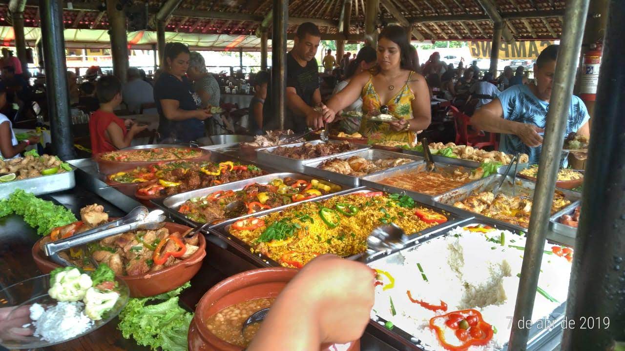 Uma pessoa está diante de uma mesa de bufê repleta de comida.