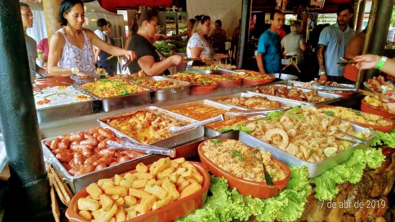 Um grupo de pessoas está em volta de uma mesa cheia de comida.