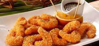 Um prato branco coberto com camarão frito e molho.