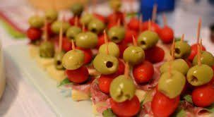 Um close de um prato de comida com azeitonas e tomates em palitos.