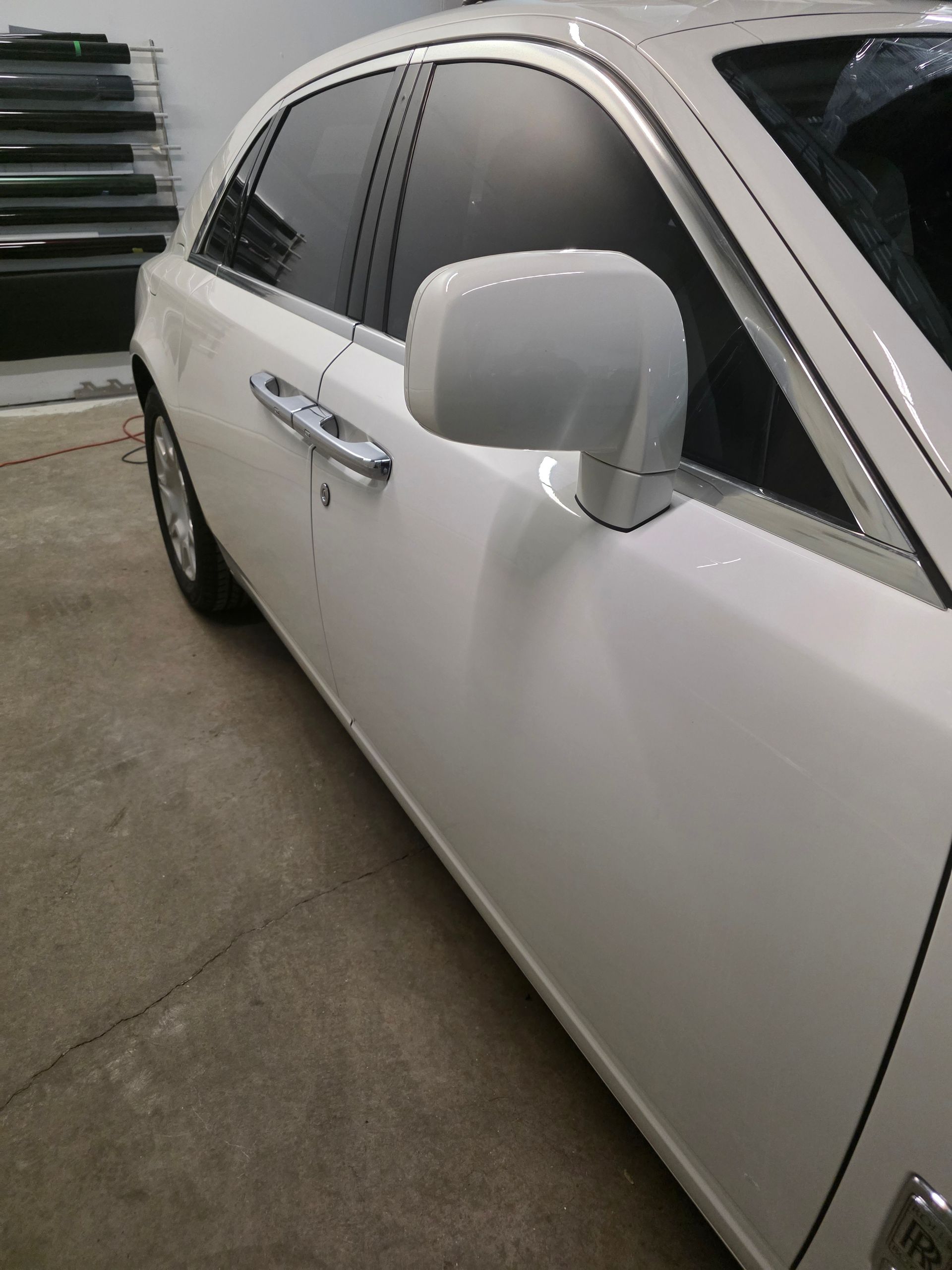 Custom white chopper motorcycle with chrome wheels and flame detailing, parked outside a detailing shop.
