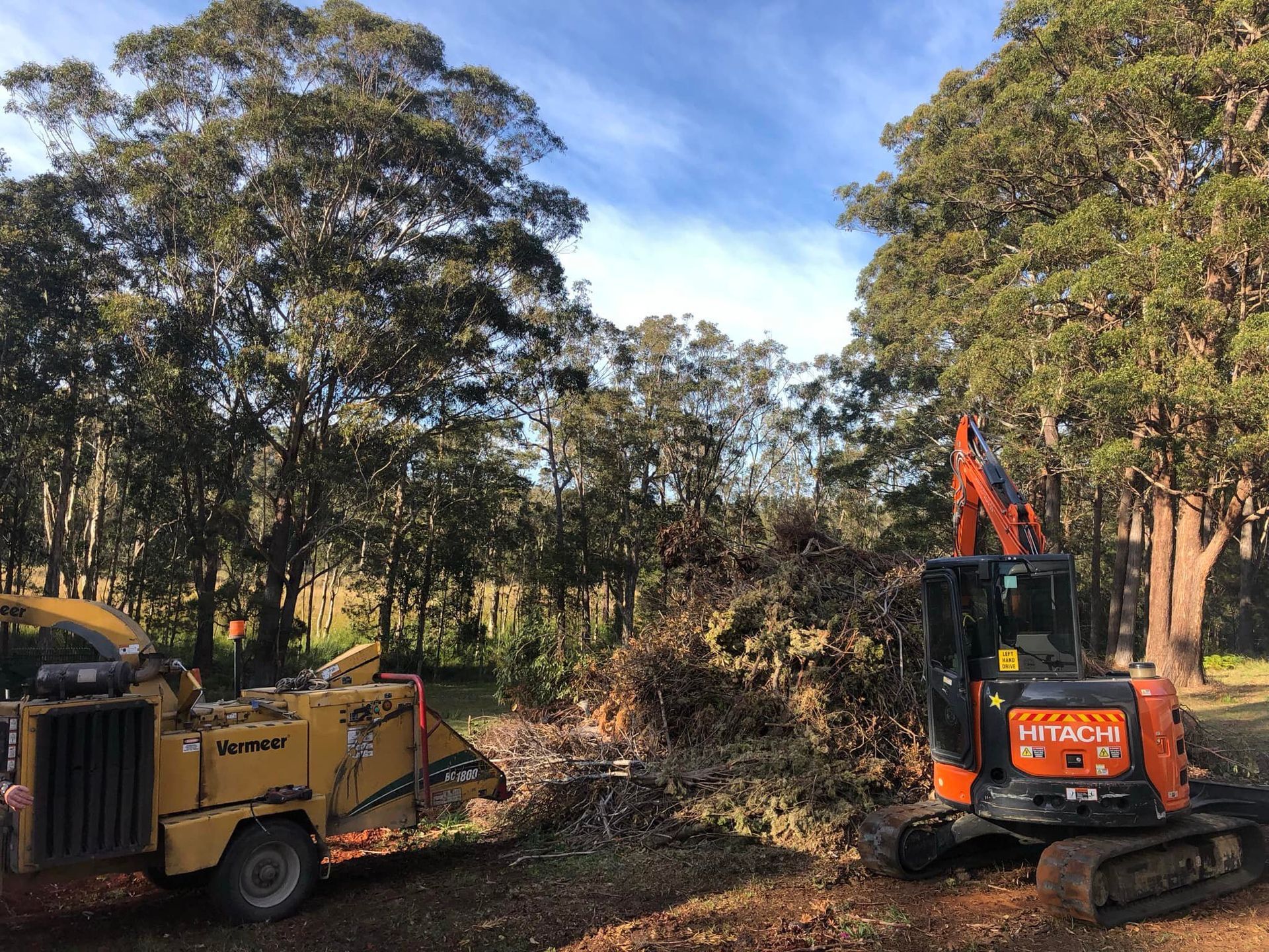 A Wood Chipper and Excavator Clearing Brush in A Wooded Area — MNC Trees in Laurieton, NSW