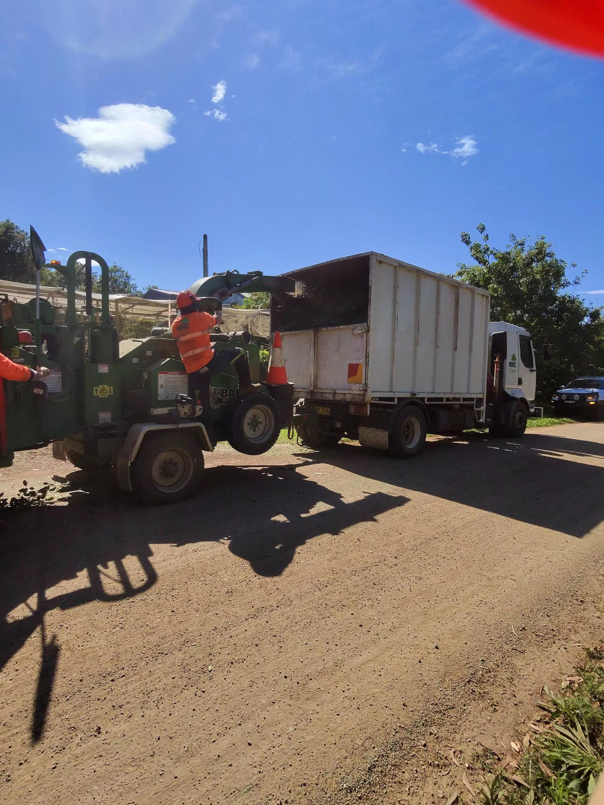 Workers Loading a White Truck With Soil Using a Small Tractor — MNC Trees in Wauchope, NSW