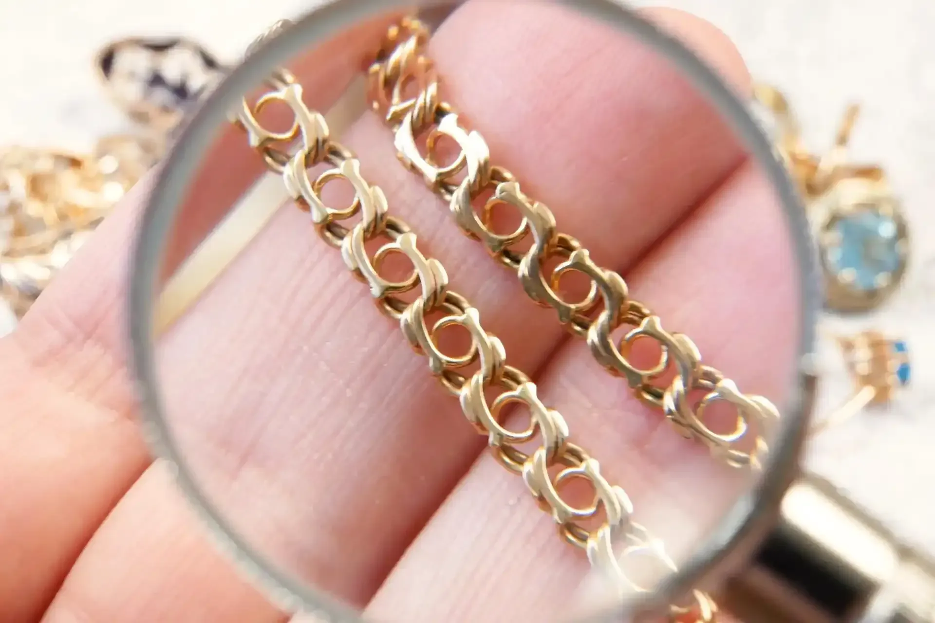 Lente d'ingrandimento su maglie di una catena d'oro tenuta tra le dita