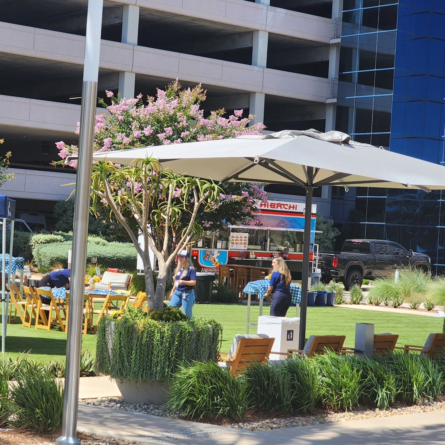 A woman stands under an umbrella in front of a parking garage