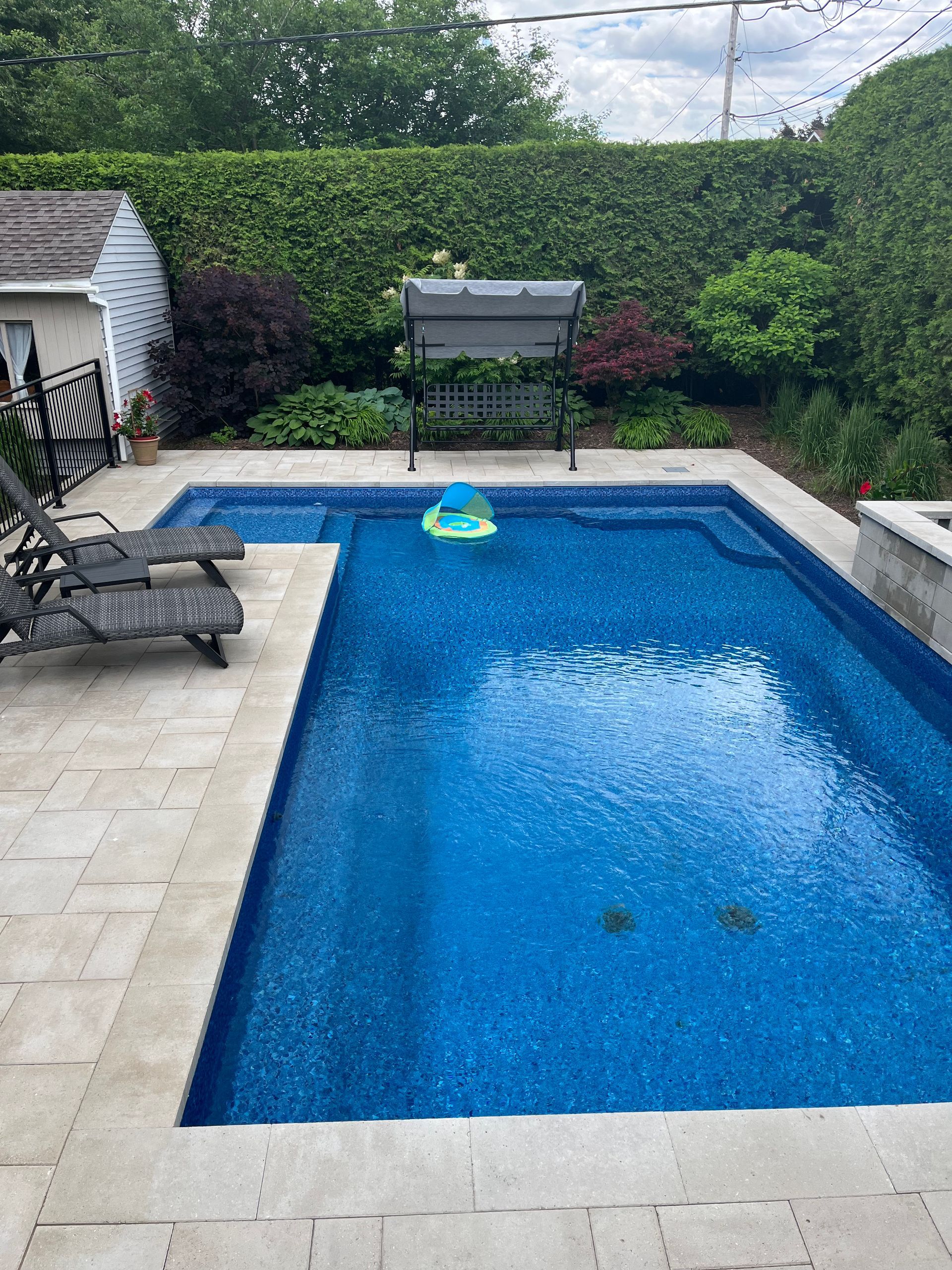 Une grande piscine entourée de chaises et d'un banc