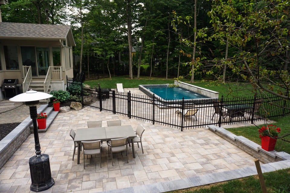 Il y a un patio avec une table et des chaises et une piscine dans l'arrière-cour.