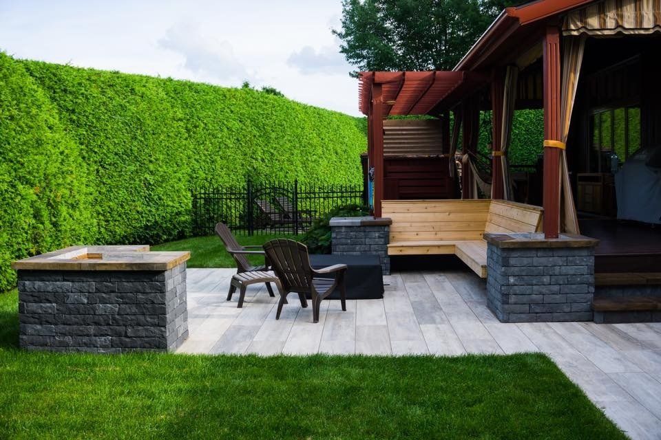 Une cour arrière avec un foyer, des chaises et un belvédère.