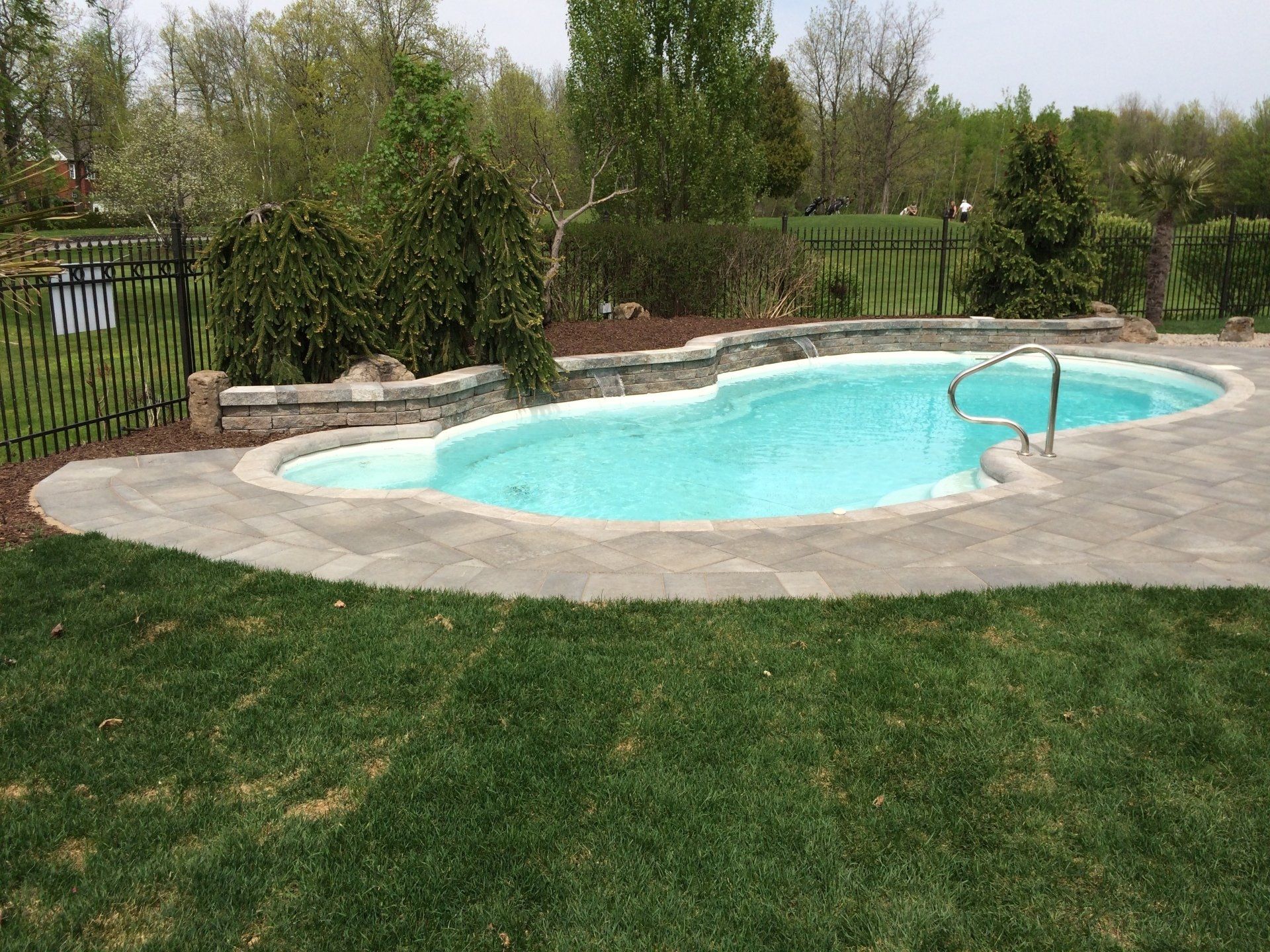 Une grande piscine se trouve au milieu d'une cour verdoyante.