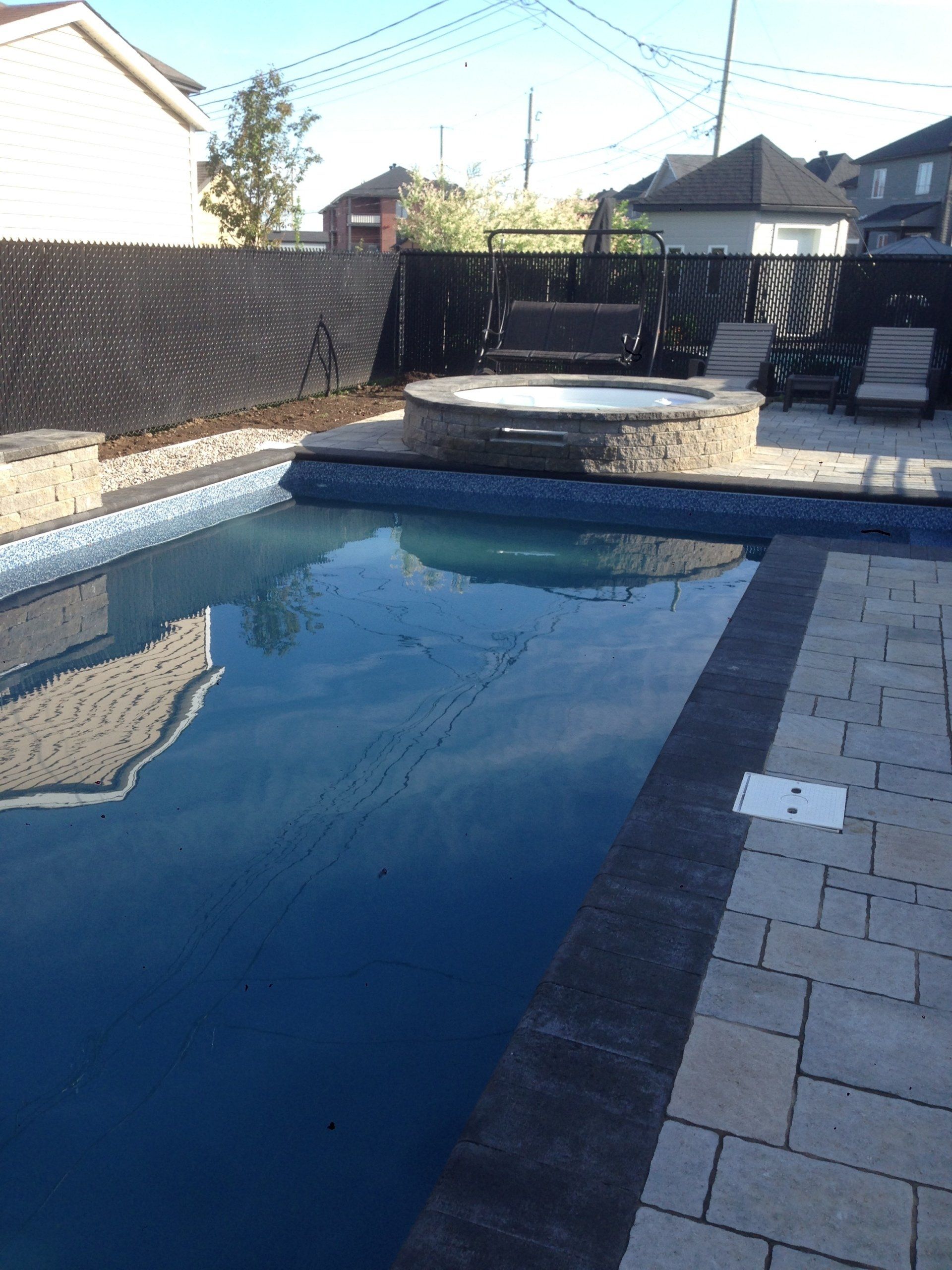 Une grande piscine avec un jacuzzi au milieu