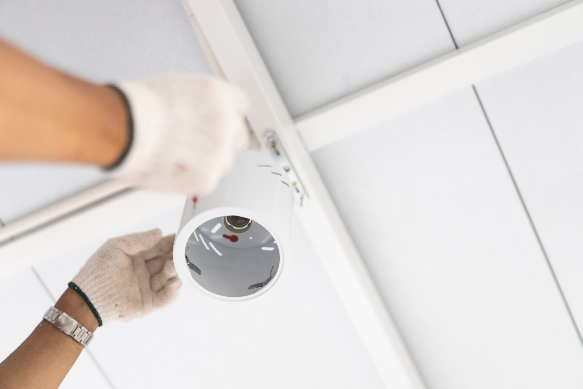 A person is installing a light fixture on the ceiling.