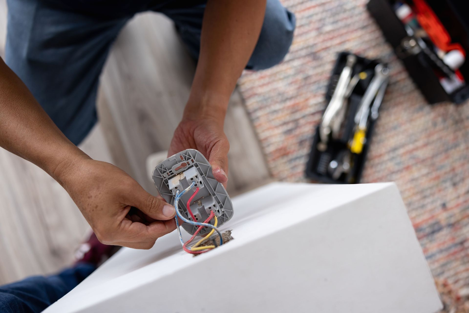 A man is fixing a light switch on a table.