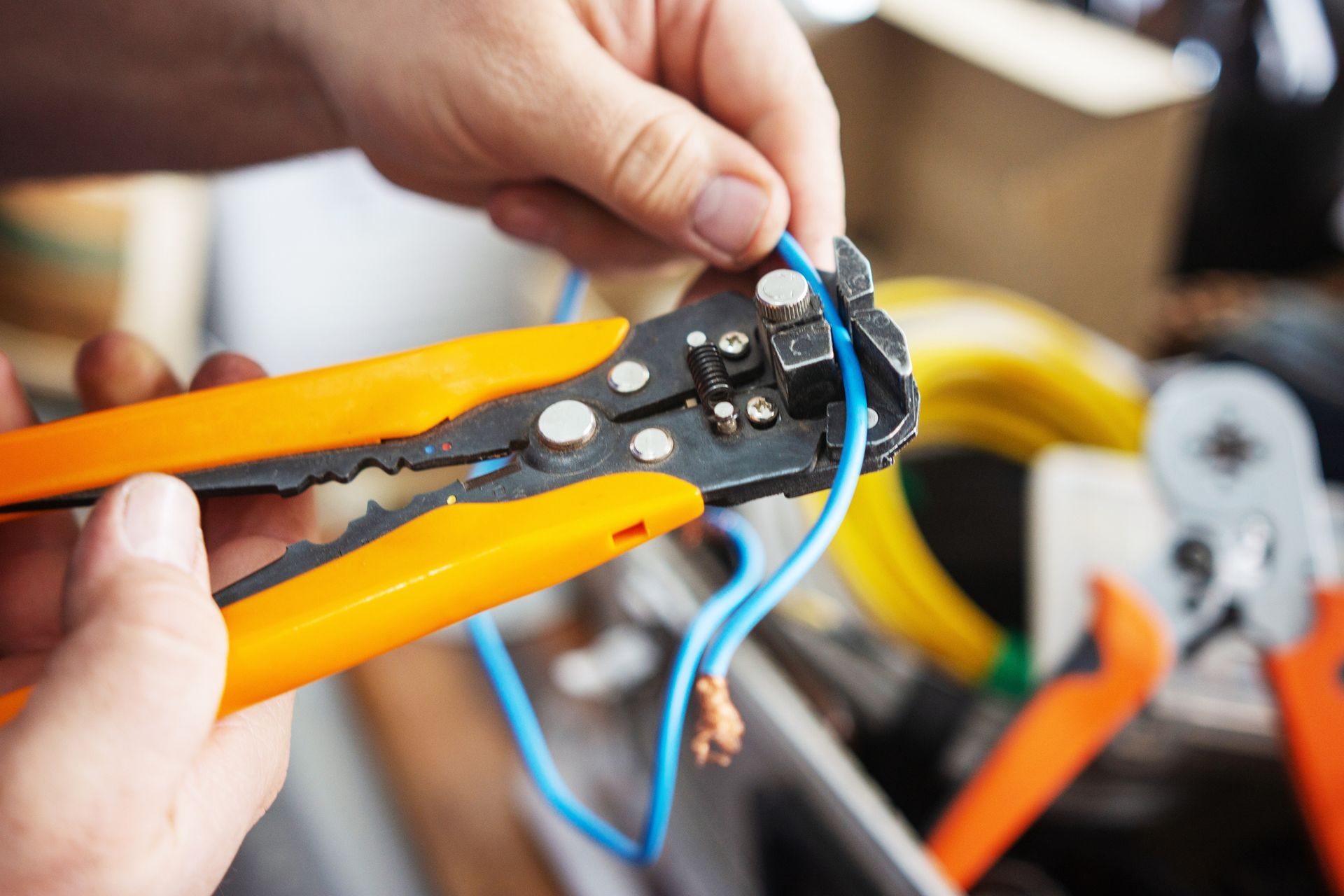 A person is using a wire stripping tool to cut a wire.