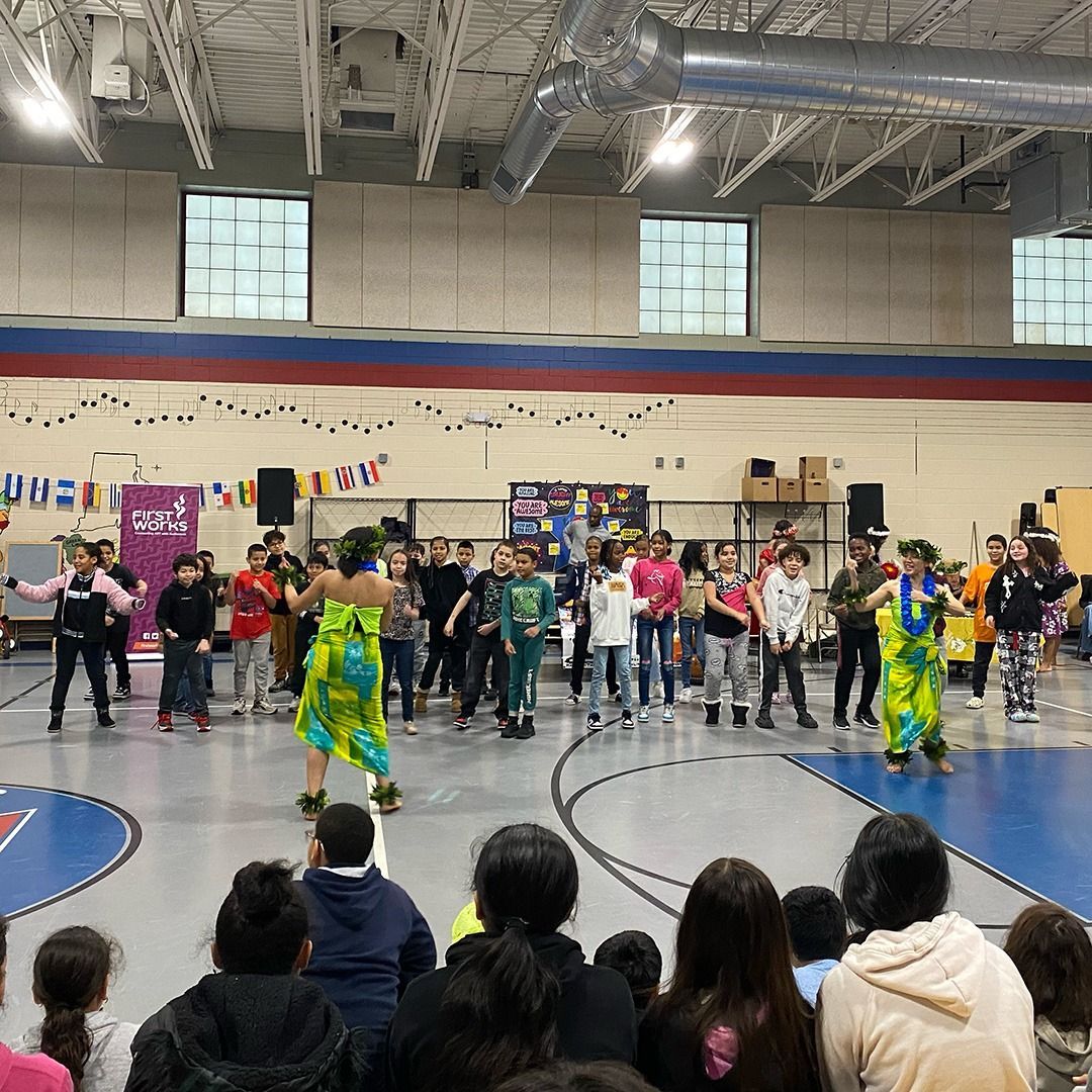 A group of people are watching a dance performance in a gym.