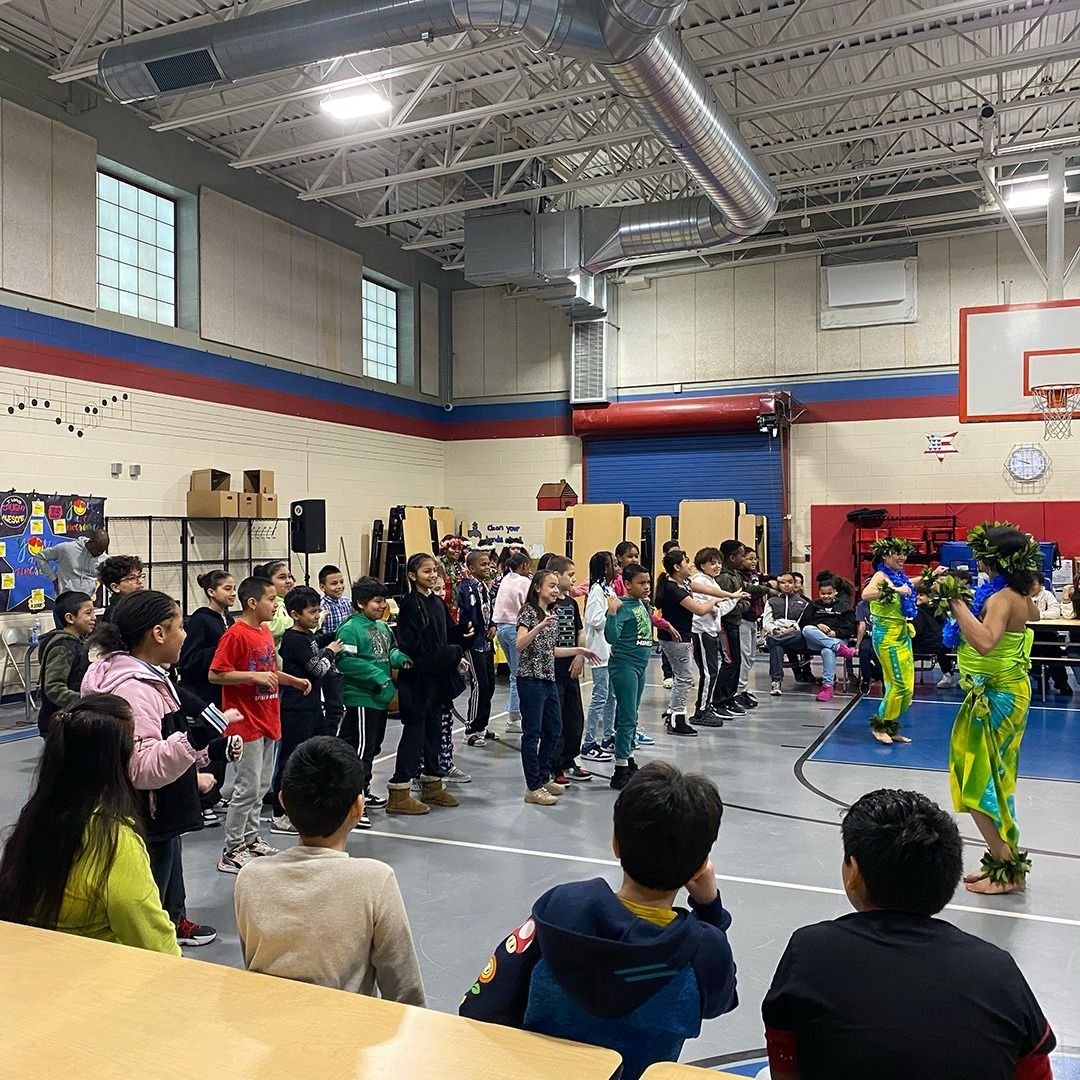 A group of children are standing around a table in a gym.