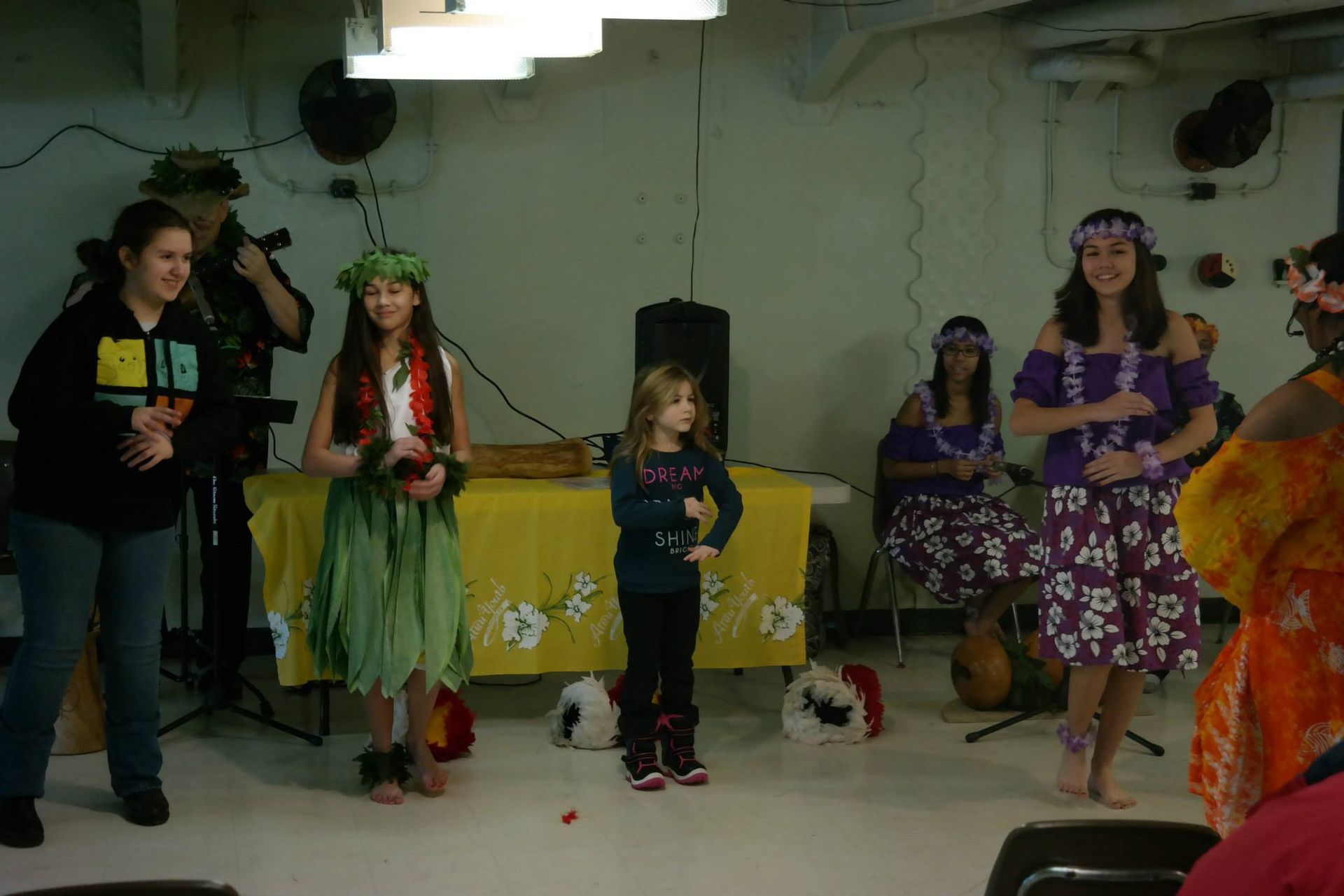 A group of people are dancing hula in a room