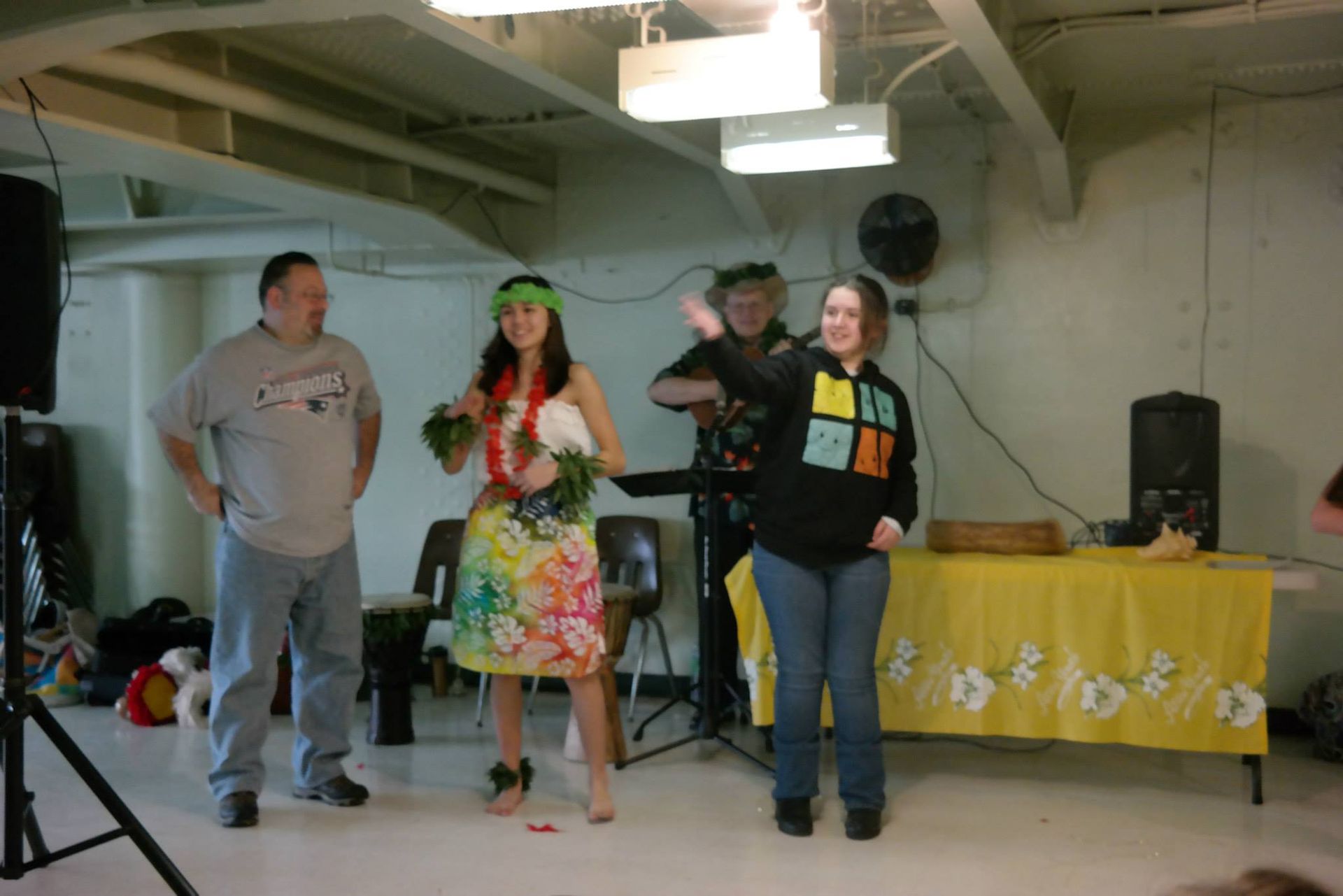 A group of people are dancing in a room with a yellow table cloth