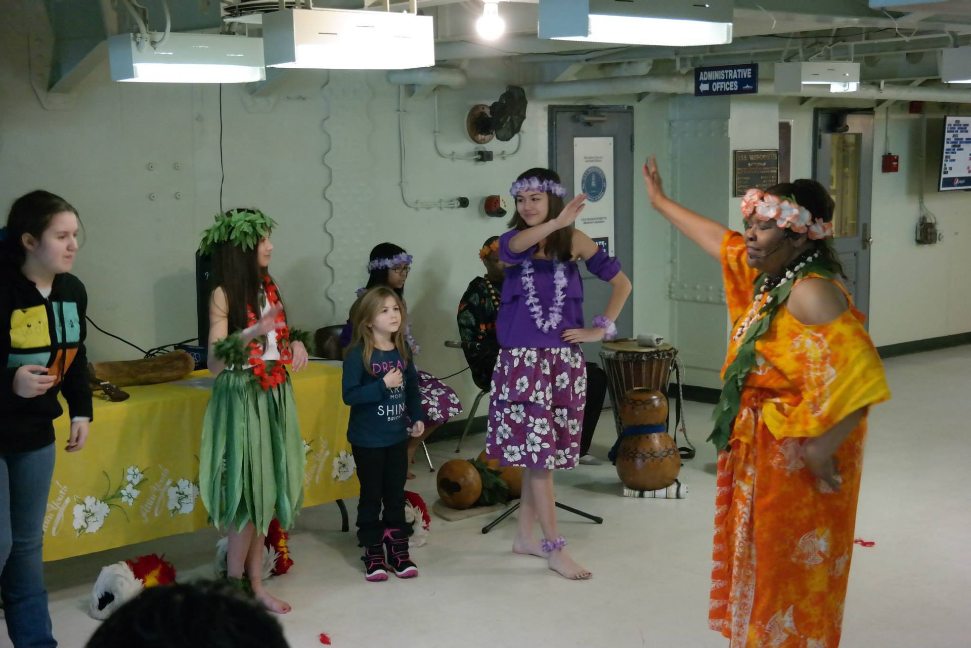 A group of people in hawaiian costumes are dancing in a room