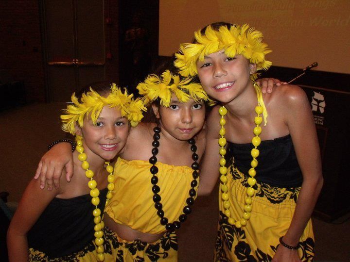 Three young girls are posing for a picture wearing yellow lei 's