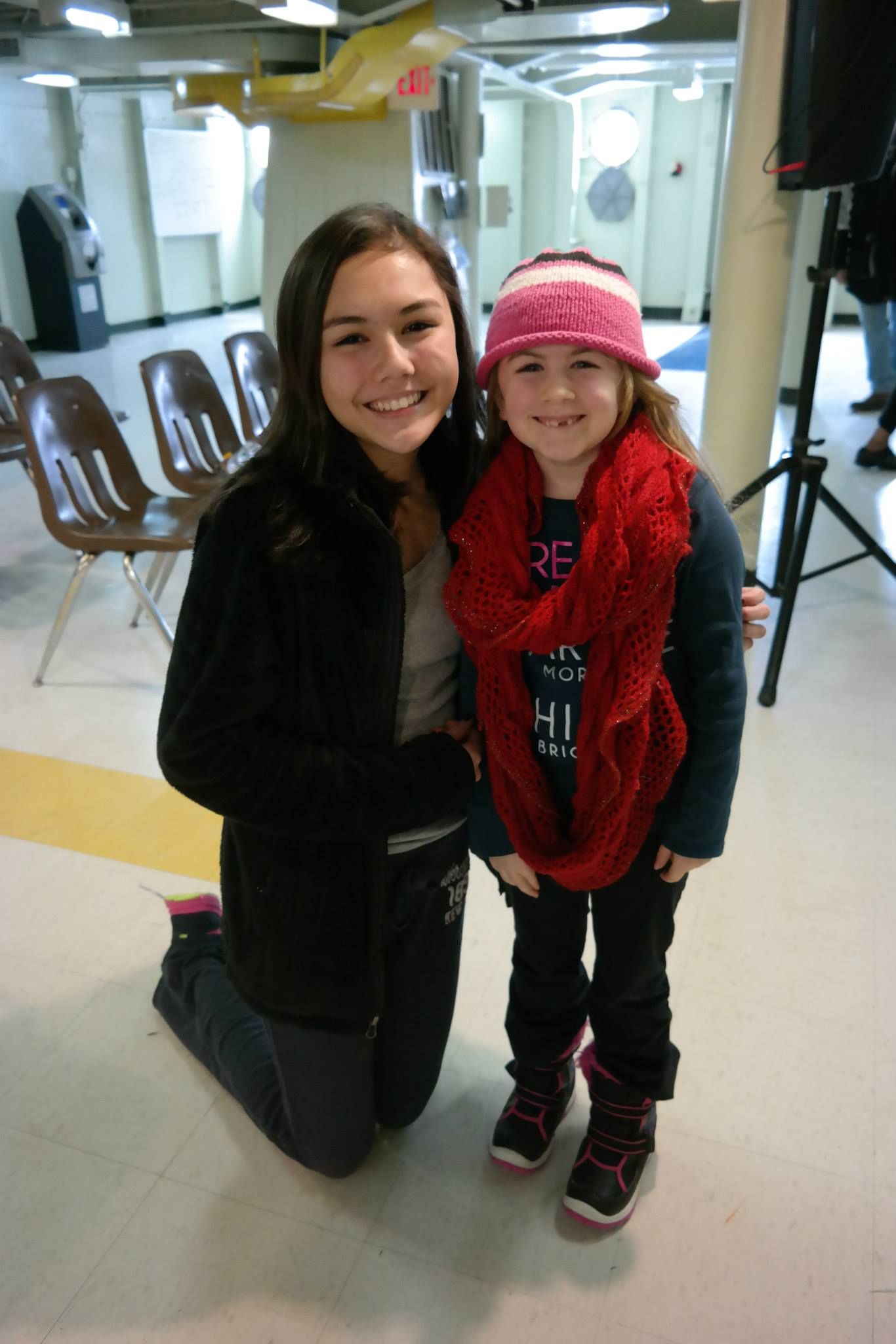 Two girls posing for a picture with one wearing a scarf that says hi