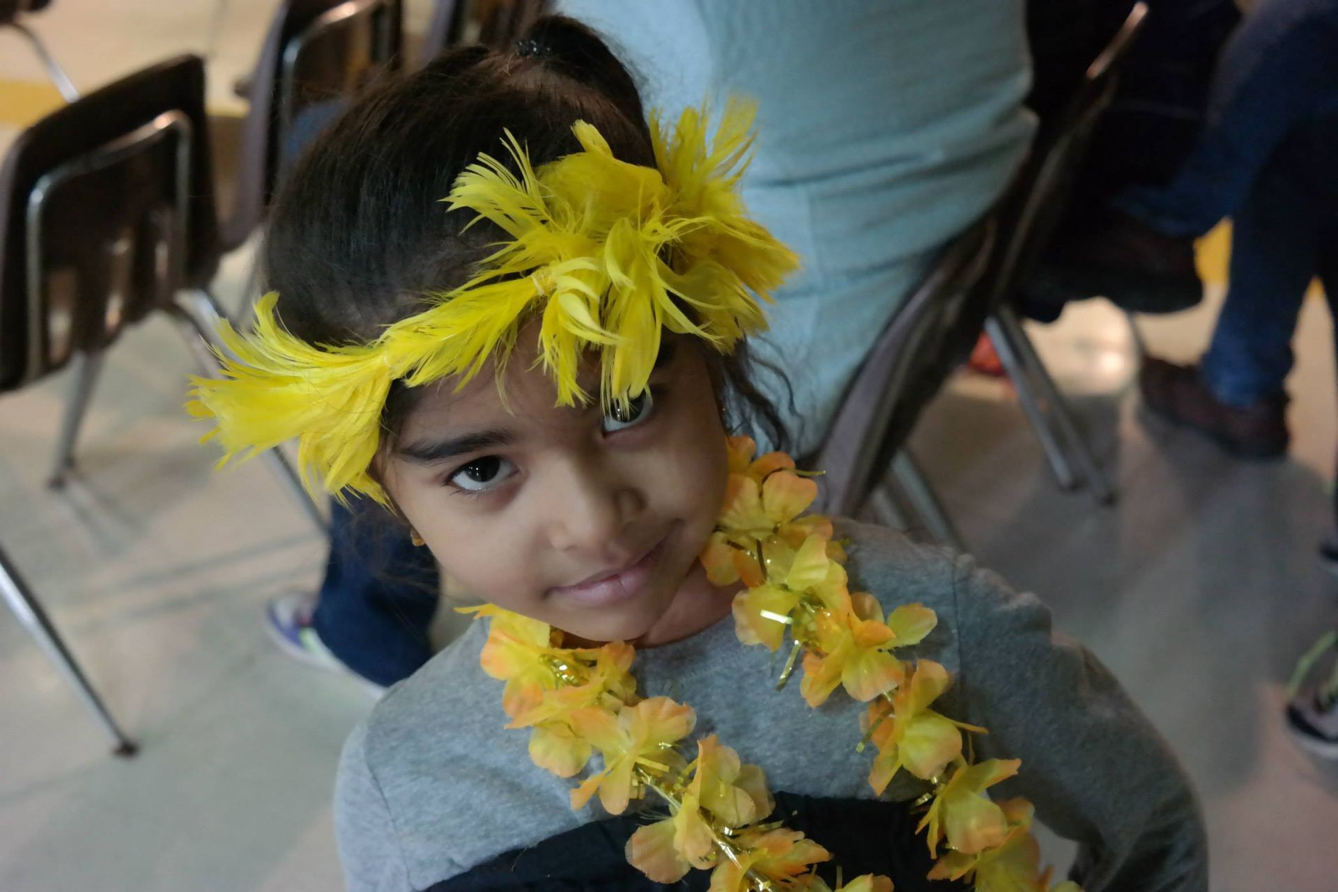 A little girl wearing a lei and a flower headband