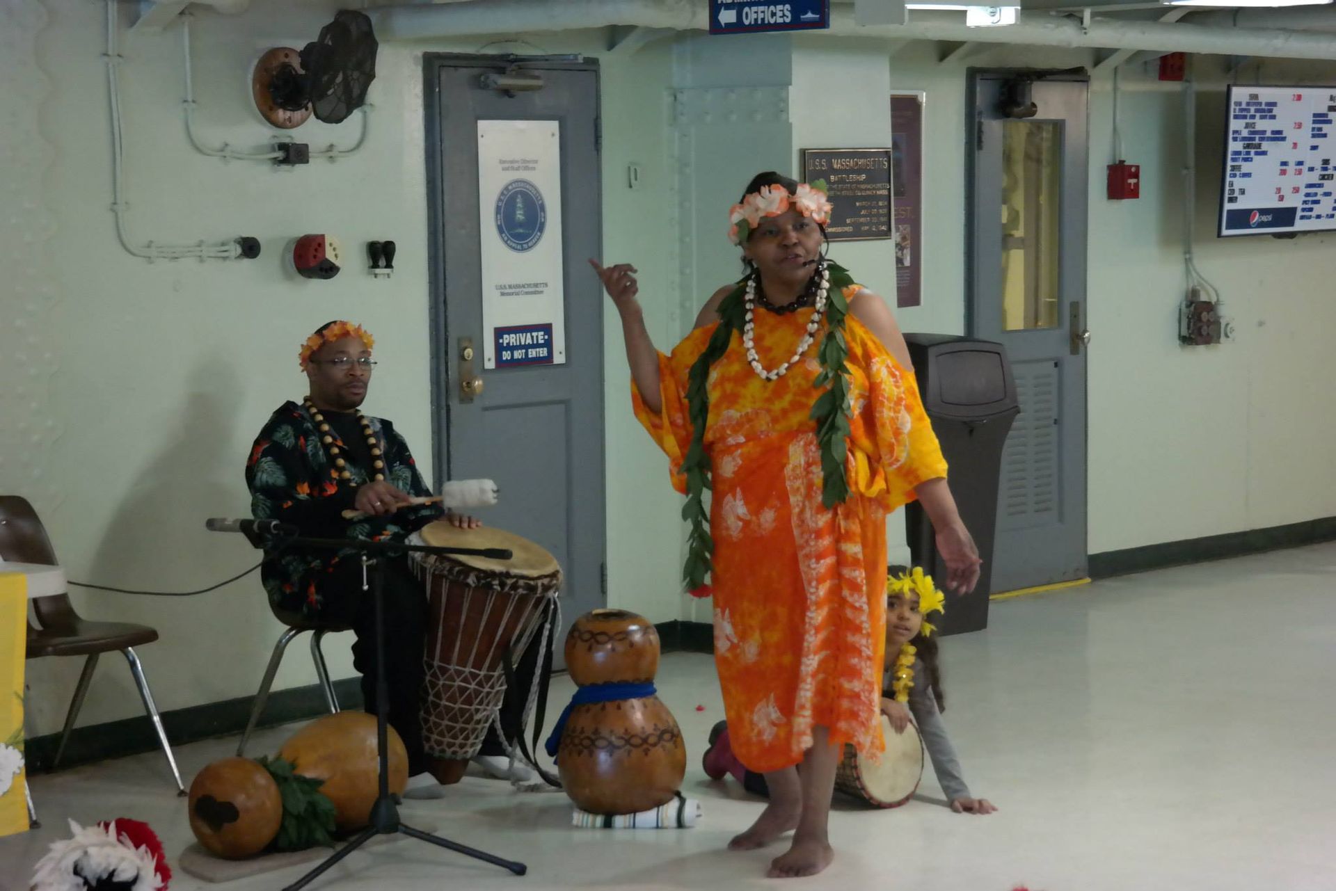 A man is playing a drum while a woman stands next to him