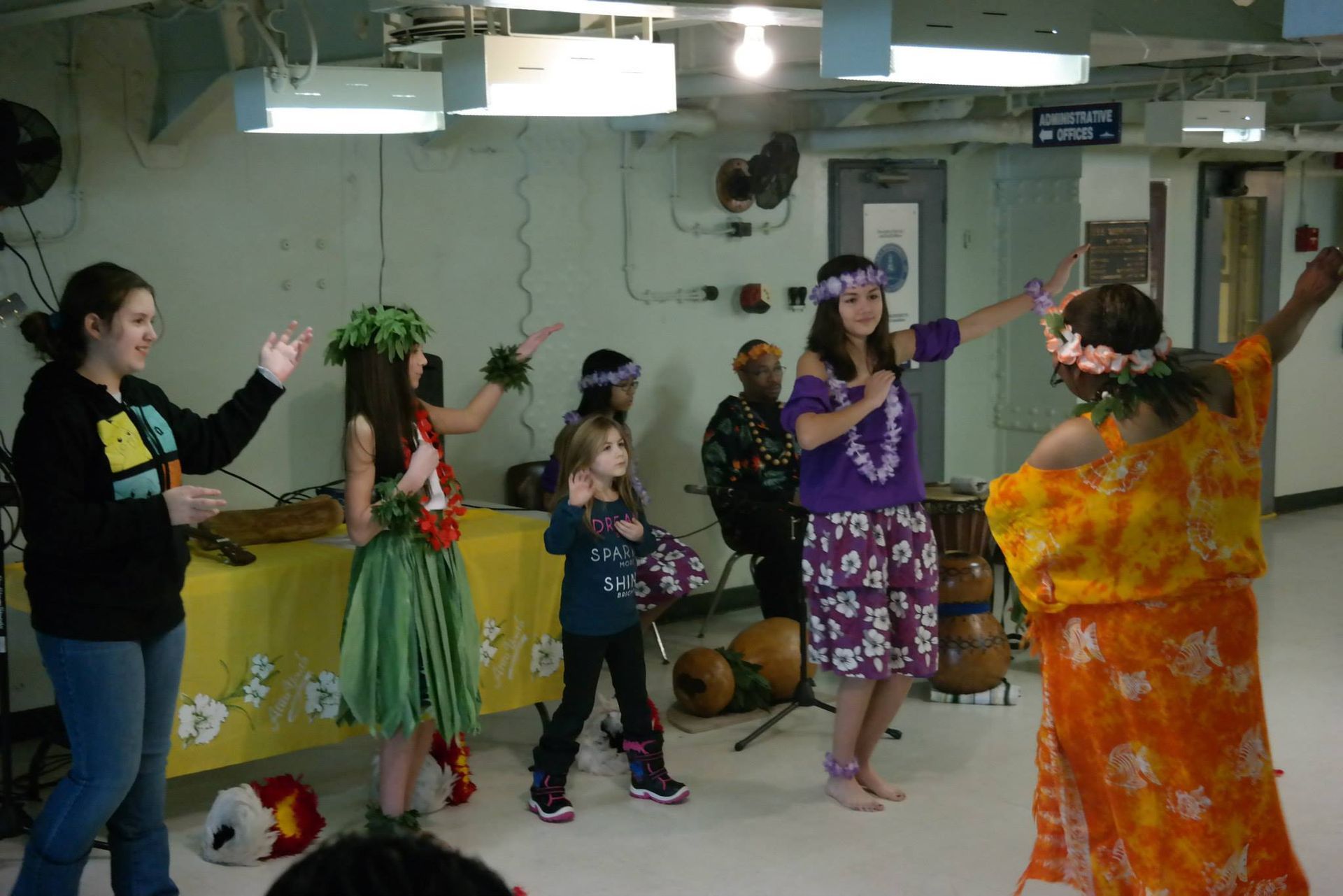 A group of people are dancing hula in a room
