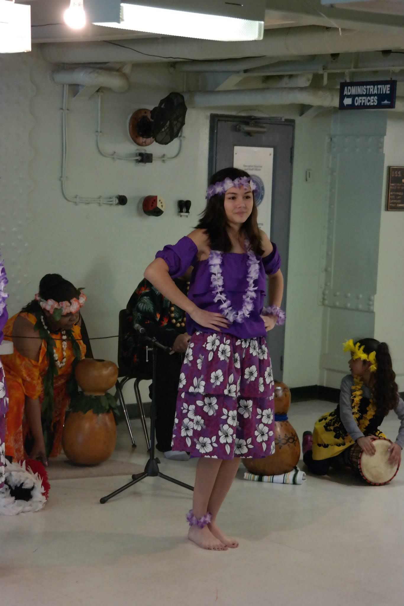 A woman in a purple hawaiian dress is dancing in a room.