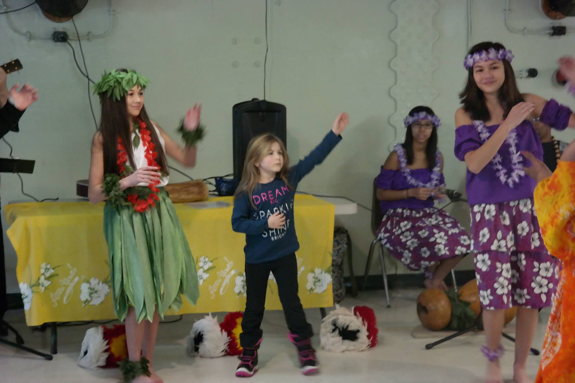 A group of girls in hawaiian costumes are dancing