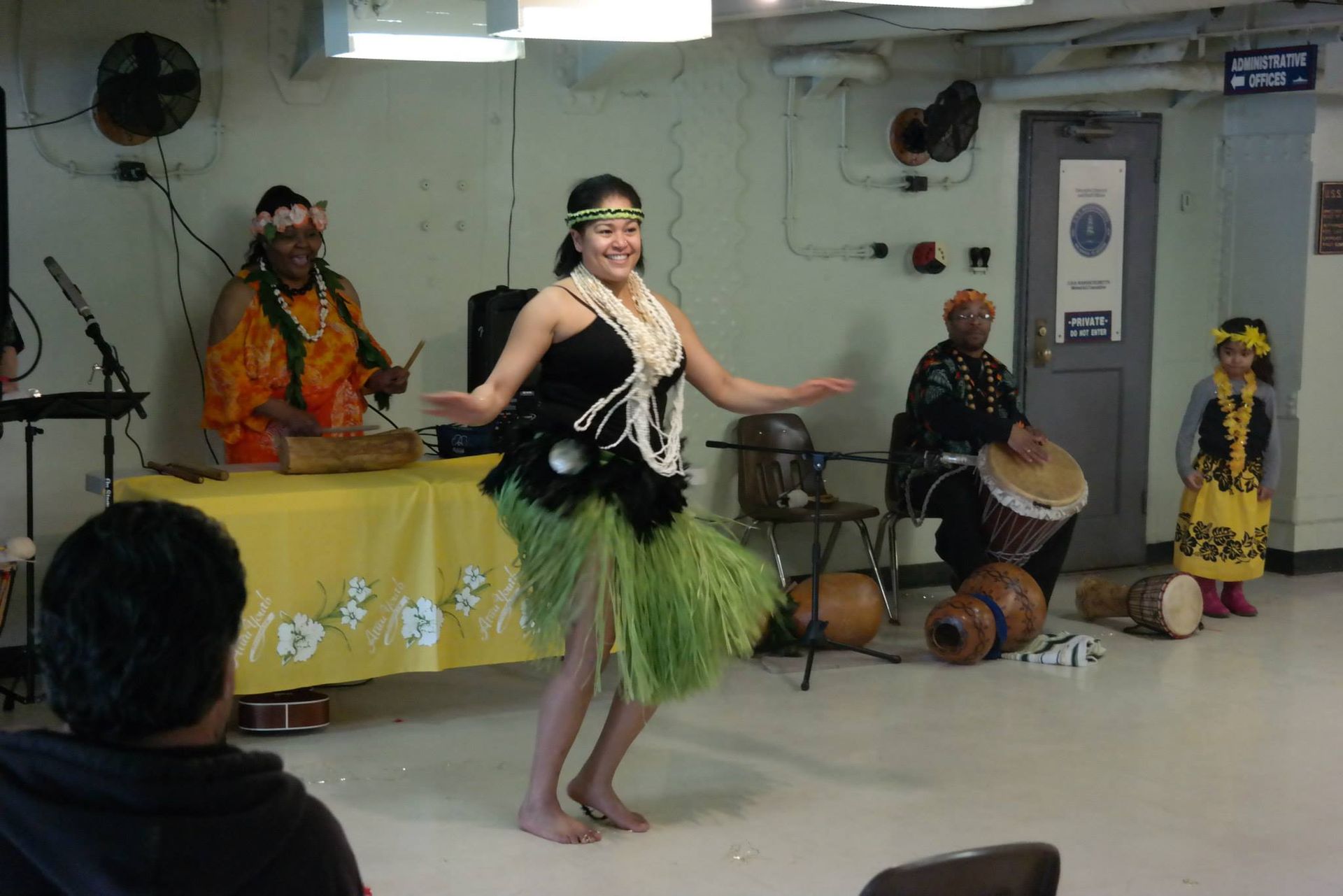 A woman in a hula skirt is dancing in front of a group of people